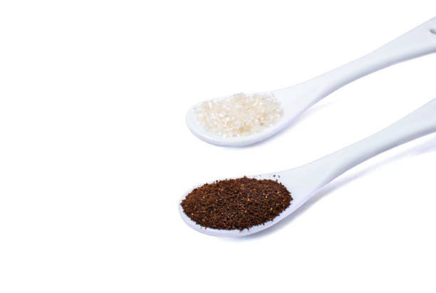 Ceramic spoons with sugar and milled coffee isolated on a white surface