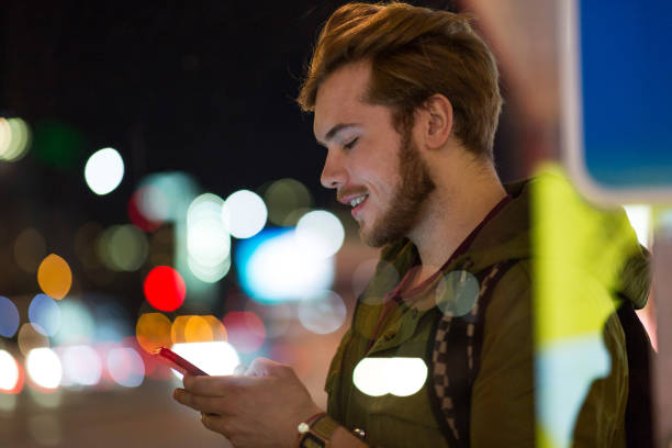 istock Young man using smartphone on urban street at night 1137583368
