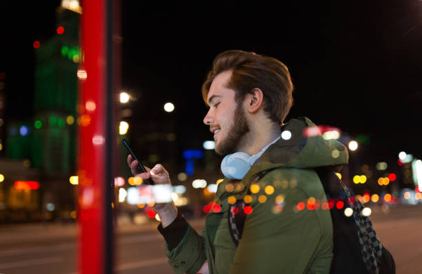 istock Young man using smartphone on urban street at night 1137583504