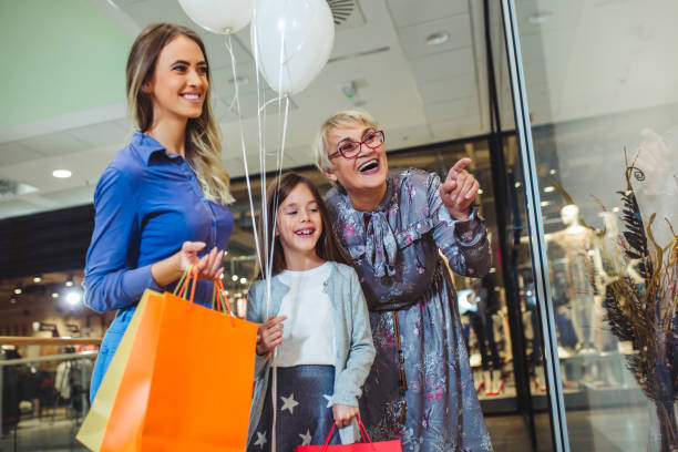 mother, adult daughter and granddaughter in shopping mall together - boutique shopping retail mother imagens e fotografias de stock