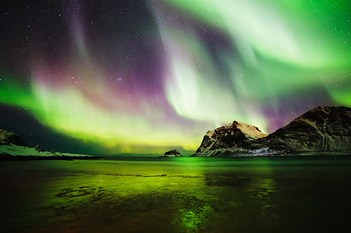 Photo of an Aurora Borealis on a beach in the Lofoten Islands in Norway.