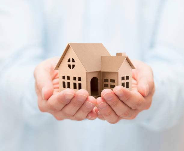 istock Property insurance. Cardboard house miniature in hands 1137590948