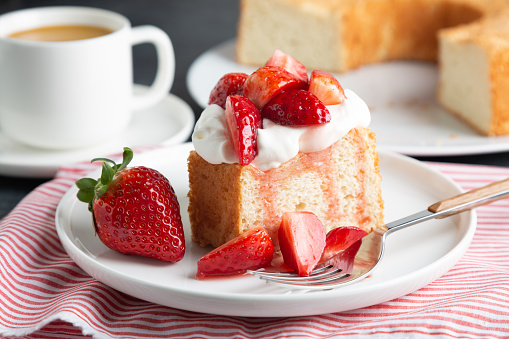 Portion of angel food cake served with whipped cream and strawberries