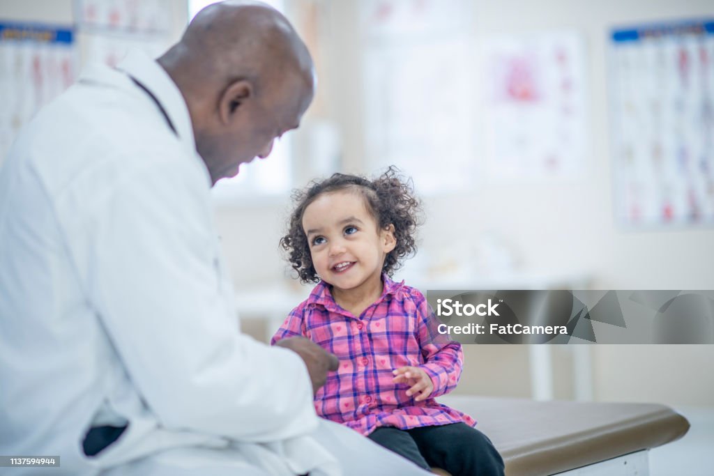 Girl At The Doctor's A doctor is comforting a young girl before her checkup. They are indoors in a medical office. Child Stock Photo