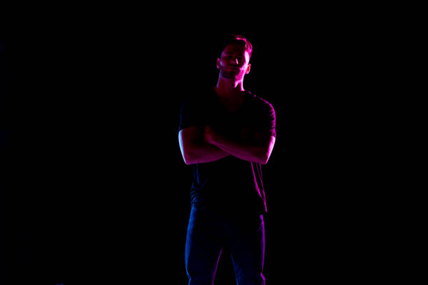 istock Handsome man with black shirt with colored gel lighting 1137601011