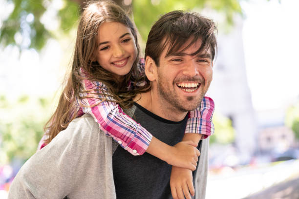 daddy carrying beautiful daughter on back having fun outside both with a toothy smile - offspring child toothy smile beautiful imagens e fotografias de stock