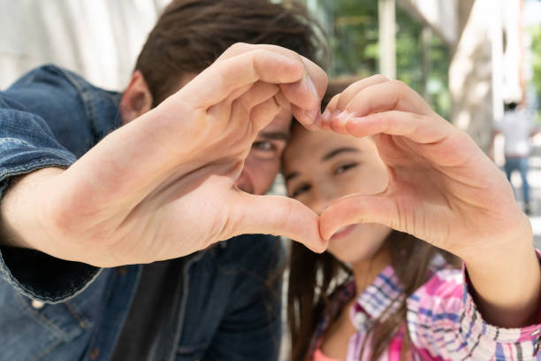 istock Cute daughter and father making a heart shape with their hands while looking at camera 1137603191