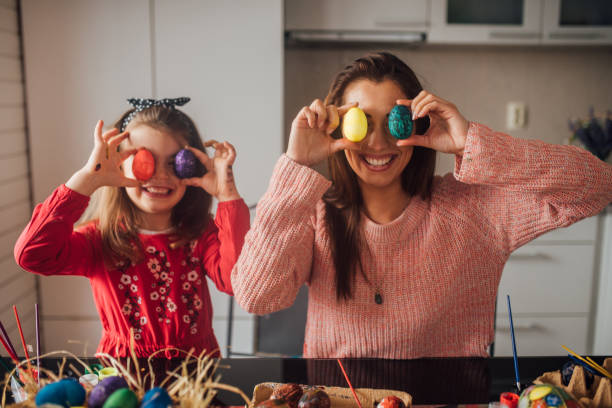 женщина и дочь играют с пасхальными яйцами - vacations two generation family holiday easter стоковые фото и изображения