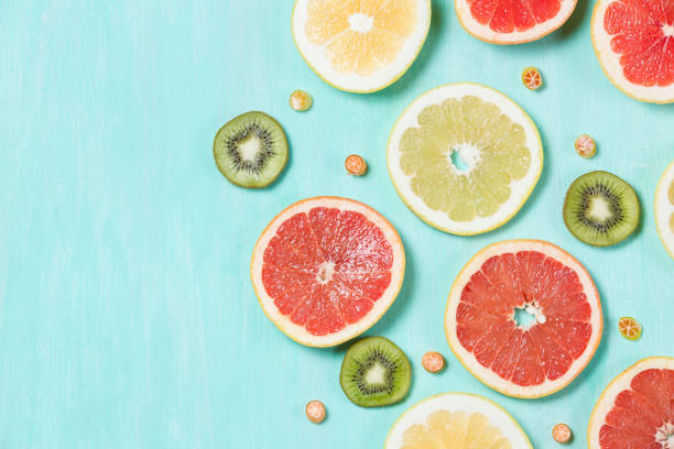 Above view on thin citrus chips: orange, lemon, grapefruit on turquoise wooden background. Vitamins