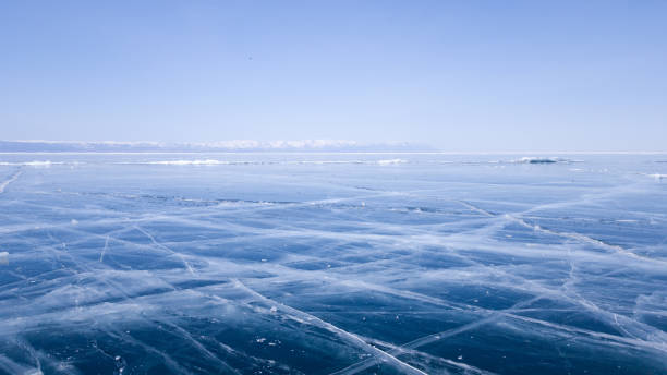 Panoramic view of the endless ice of lake Baikal in winter. Deep cracks on the surface of bright blue ice. Sunny clear weather in frosty Siberia stock photo