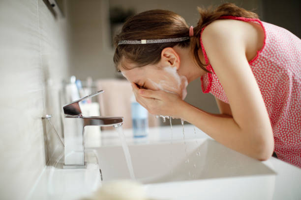 adolescente che si lava il viso con acqua - detergente per il viso foto e immagini stock