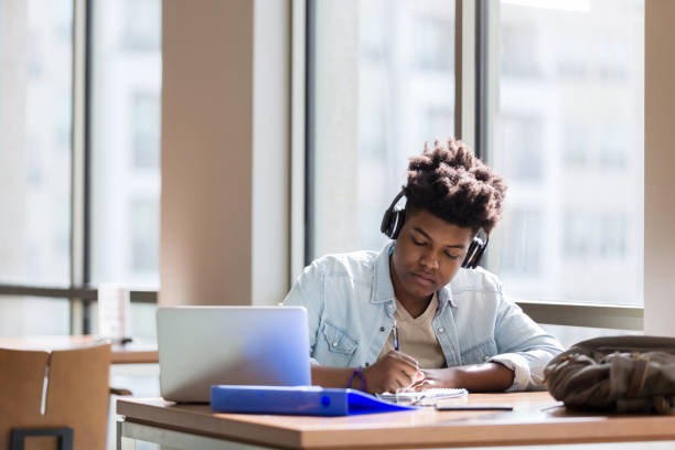 istock High school student studies to music in library 1137620342