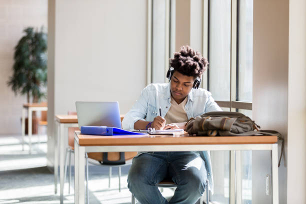 istock Teen boy studies to music in library 1137620345