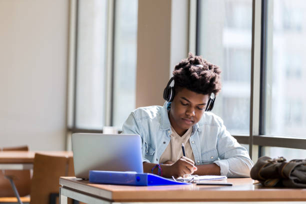 istock Teen boy does homework in high school library 1137620347