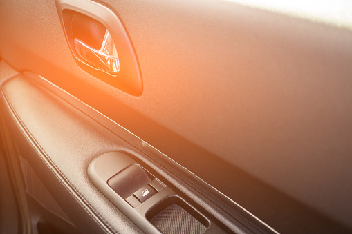 Car interior details of door handle with windows controls. Car window controls and details.