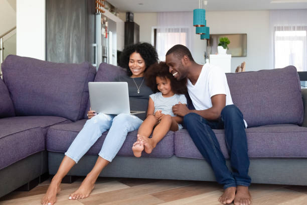 feliz familia afroamericana con hija usando laptop en casa - family american culture black child fotografías e imágenes de stock