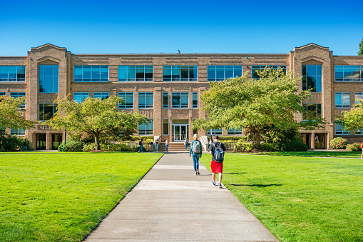 Students walk toward Shiley Hall on the University of Portland campus in Portland Oregon USA on a sunny day.