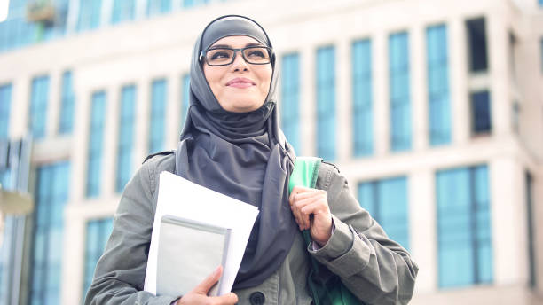 istock Inspired young female student wearing hijab smiling, standing outdoors on campus 1137645446