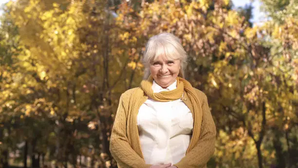 Attractive mature woman posing at camera on background of autumn weather