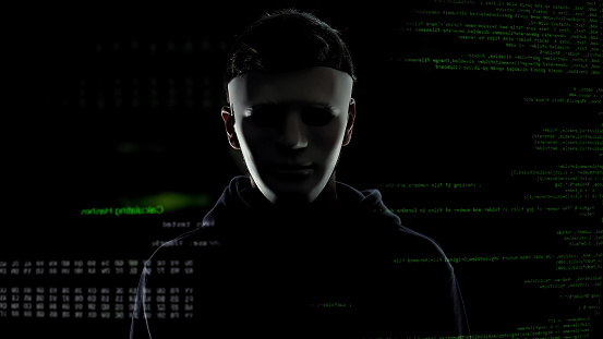 Dangerous man in white mask on codes and numbers background, hacking concept
