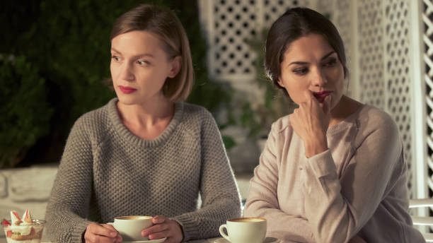 カフェに座っている2人の動揺する女性の友人、関係の対立�、誤解 - 姉妹 ストックフォトと画像