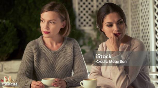 Two Upset Female Friends Sitting In Cafe Relations Conflict Misunderstanding Stock Photo - Download Image Now