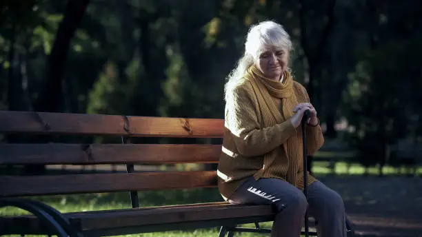 Sad lonely old woman sitting on bench in park, abandoned elderly people alone