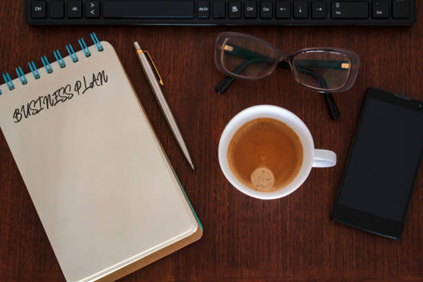 istock Top view of Office desk with office accessories and notebook with Business Plan written. Business plan strategy concept 1137646574