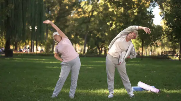 Mom and her daughter doing workout in park, healthy lifestyle in elder age