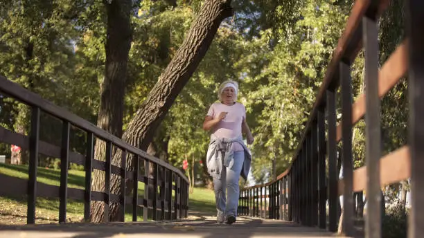 Fit elderly woman running in park, soul youth morning exercise and health