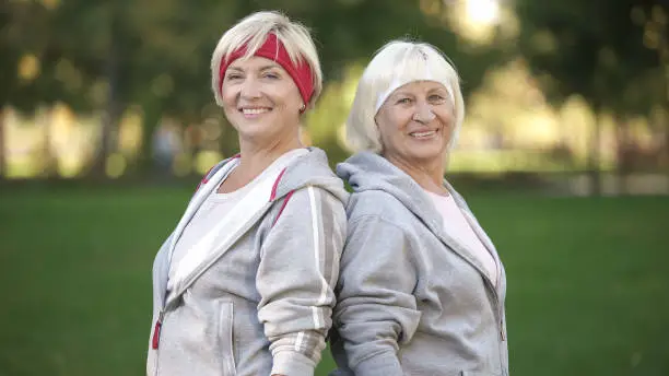 Cheerful women in sport suits smiling after workout in park, healthy lifestyle