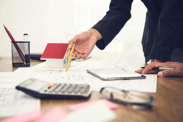 istock Real estate agent discussing work with blueprints and house model on the table 1137648356