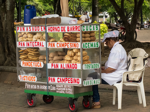 Cali, Colombia - February, 2019: Female street vendor of different types of traditional breads in Cali