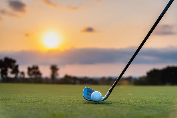 golfeur met la bille de golf sur l'herbe verte au terrain de golf pour frapper au trou avec le fond de flou et le rayon de lumière du soleil - golf golf swing sunset golf course photos et images de collection
