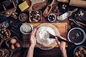 Woman hands making chocolate mousse and cookies on a wooden table in a rustic kitchen