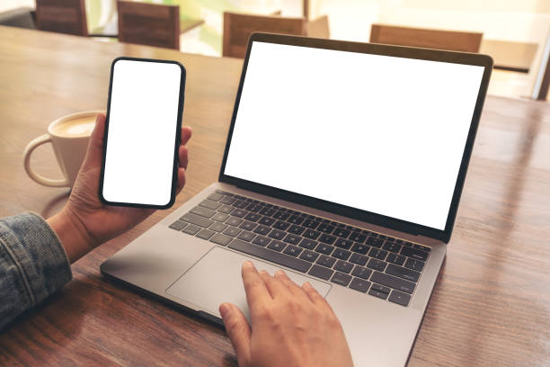 istock a woman touching on laptop touchpad with blank white desktop screen while using mobile phone 1137683434