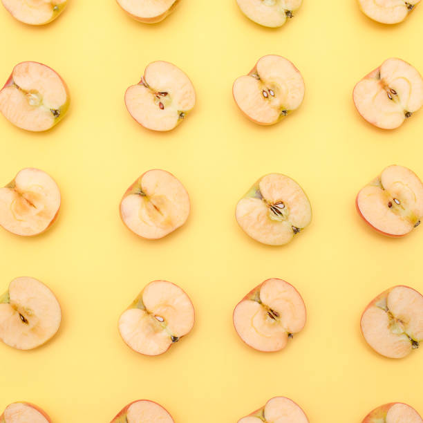 istock Background of cut in half apples on yellow background 1137690499