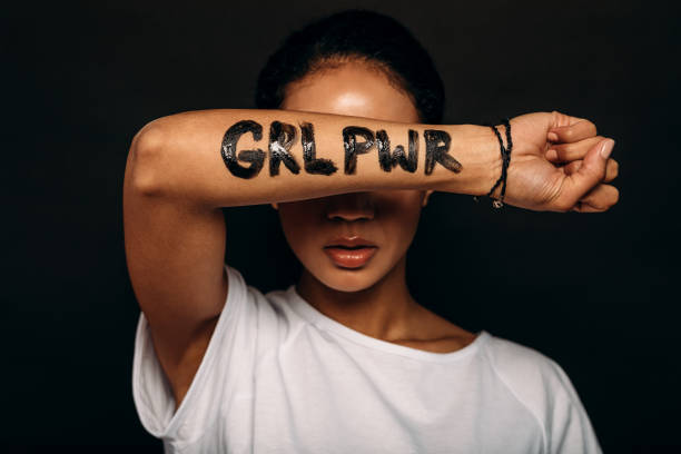 Woman with letters "GRL PWR" written on her hand. Woman with letters "GRL PWR" written on her hand. Portrait of a woman with arm covering a part of her face. womens rights stock pictures, royalty-free photos & images