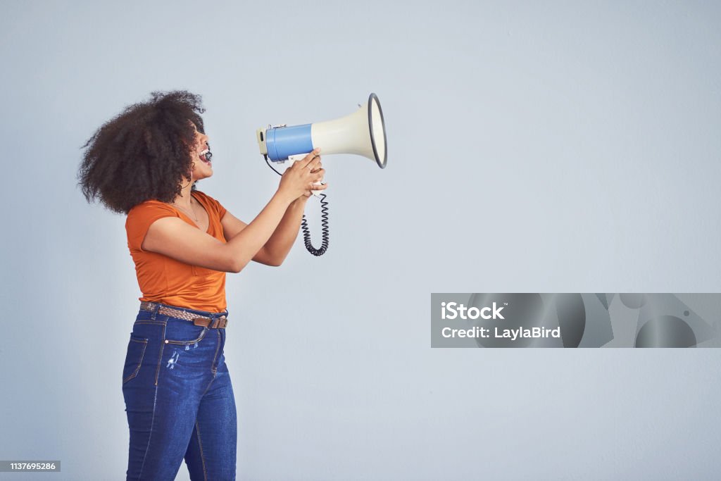 Take a stand for every woman out there Studio shot of a young woman using a megaphone against a gray background Megaphone Stock Photo