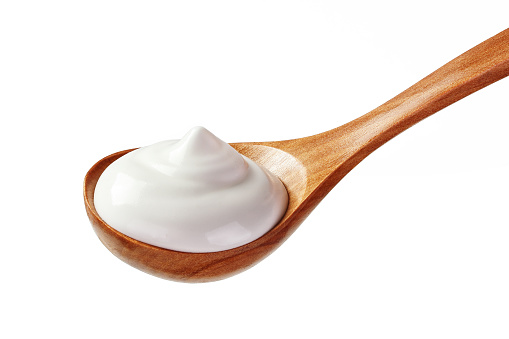 cream sour in a spoon  isolated white backround close up