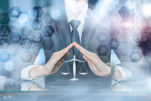 istock A businessman with his hands in protective position under scale of justice on a tablet. 1137700188