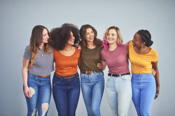 Friends make the world a happier place Studio shot of a group of attractive young women embracing against a gray background womens rights stock pictures, royalty-free photos & images