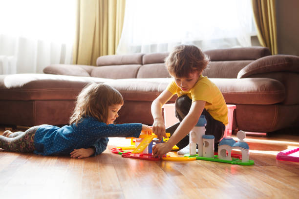 schattige twee kleine kinderen spelen met speelgoed thuis - broer en zus stockfoto's en -beelden