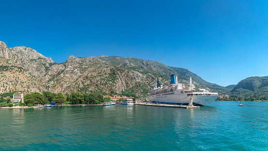 Kotor, Montenegro - 07.11.2018.  View from the sea to the cruise liner at the pier of the old town of Kotor and fortification wall around the city in Montenegro in a sunny summer day