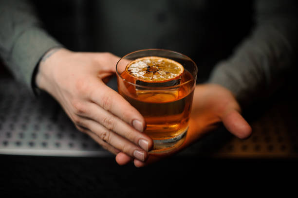 istock Bartender serving a delicious brown cocktail with a dried orange 1137705319