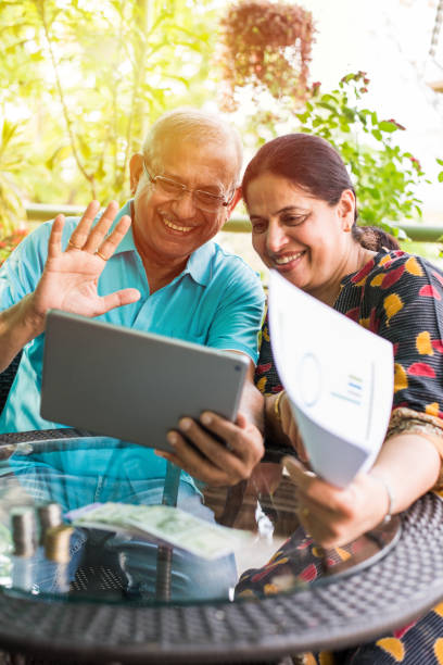 istock Indian/asian Senior couple video chatting on tablet/computer while sitting at couch or in garden at home, selective focus 1137709312