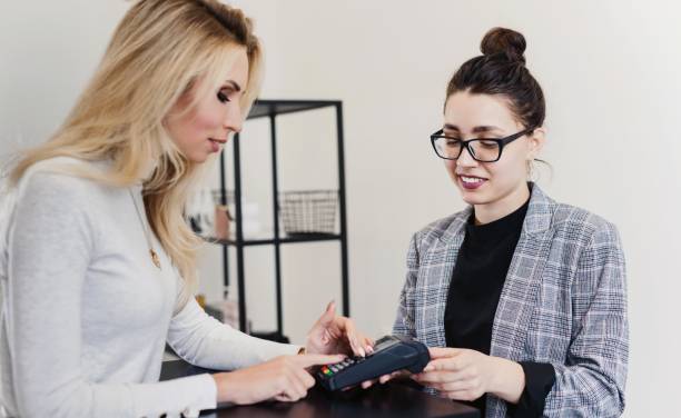 istock Young beautiful woman happy customer making wireless or contactless payment using her mobile phone. Smiling cashier accepting payment over nfc technology 1137719565