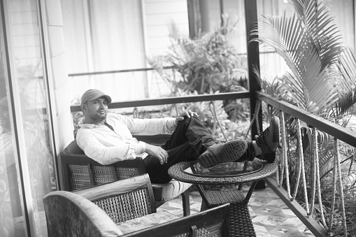 Handsome young men resting or relaxing in balcony of luxury tourist resort in Goa.