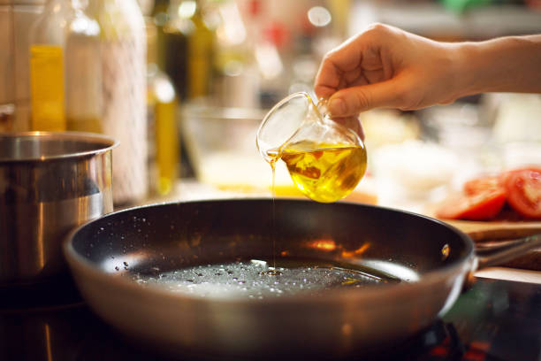 cook pours oil on a skillet cook pours oil on a skillet skillet cooking pan photos stock pictures, royalty-free photos & images