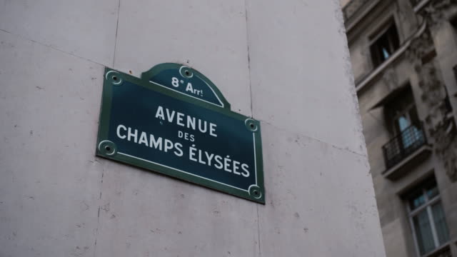 Classic street sign of Avenue Champs Elysees or Elysian Fields located on a house in Paris. France. Shot with parallax effect relative to houses in the background. Illustration of shopping and expensive shops on Avenue des Champs-Élysées